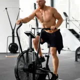 Mężczyzna ćwiczy na rowerze stacjonarnym po treningu siłowym. Zastanawia się, ile cardio jest optymalne.