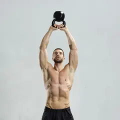 Mężczyzna wykonuje ćwiczenie z kettlebell. Kettlebell swing jakie mięśnie pracują? Mięśnie brzucha, pośladków i ud są mocno zaangażowane.