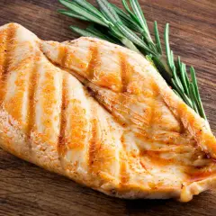 Grillowana pierś z kurczaka z rozmarynem na drewnianej desce. Dowiedz się, ile białka ma pierś z kurczaka.