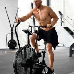 Mężczyzna ćwiczy na rowerze stacjonarnym po treningu siłowym. Zastanawia się, ile cardio jest optymalne.