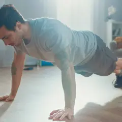 Mężczyzna wykonuje pompki w domu, ćwicząc swój trening metaboliczny.