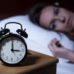 Kobieta nie może zasnąć, budzik pokazuje 3:00. Czy to melatonina skutki uboczne?