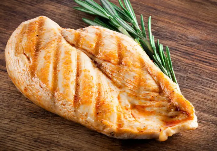 Grillowana pierś z kurczaka z rozmarynem na drewnianej desce. Dowiedz się, ile białka ma pierś z kurczaka.