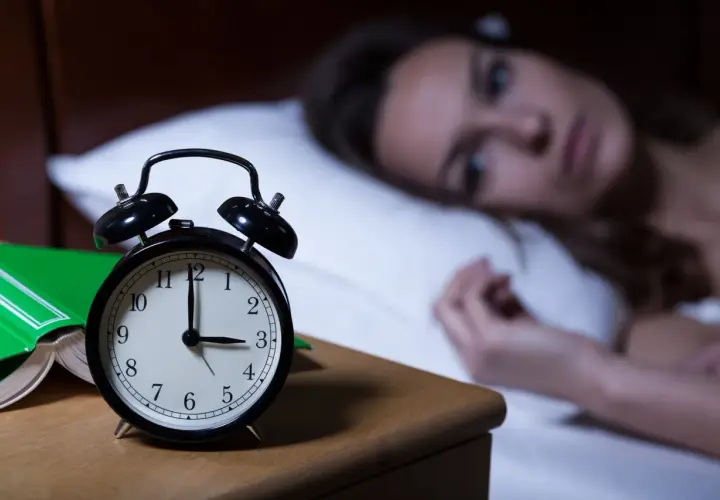 Kobieta nie może zasnąć, budzik pokazuje 3:00. Czy to melatonina skutki uboczne?
