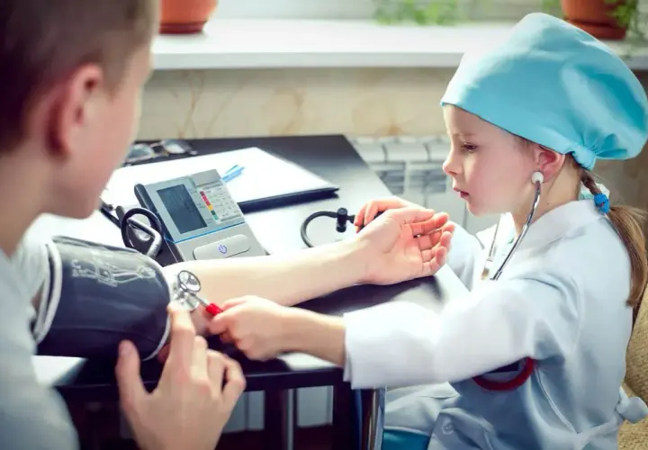 Dziecko w stroju lekarza mierzy ciśnienie. Czy tauryna podnosi ciśnienie? To pytanie, na które odpowiedzi szukają mali medycy.