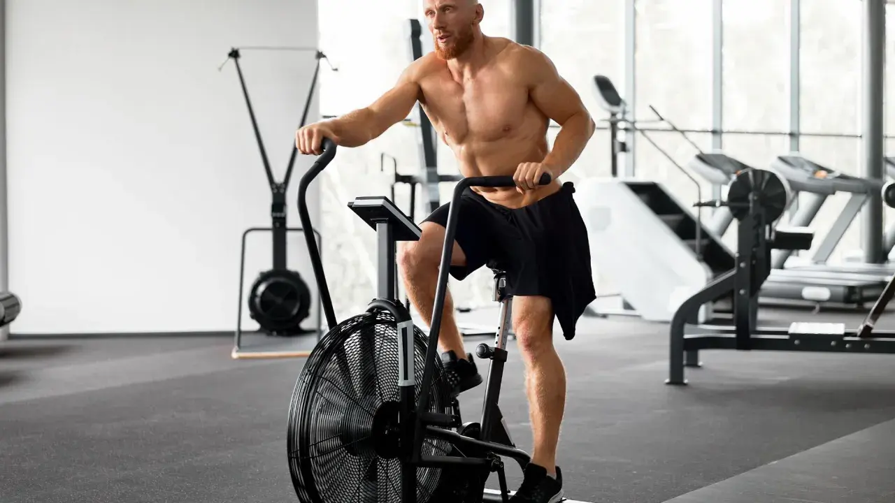 Mężczyzna ćwiczy na rowerze stacjonarnym po treningu siłowym. Zastanawia się, ile cardio jest optymalne.