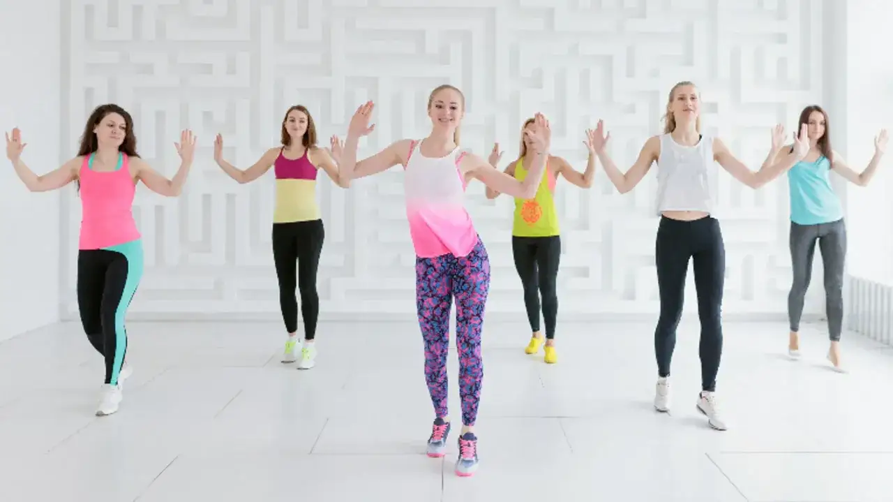 Grupa kobiet ćwiczy salsation. To taneczna forma fitnessu, która łączy ruch z muzyką.