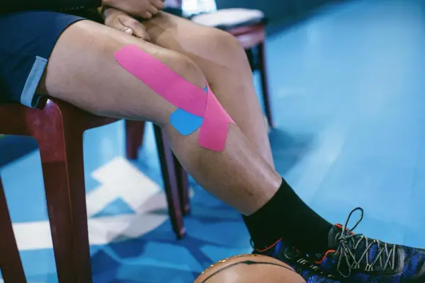 Chondromalacja rzepki ćwiczenia: sportowiec z plastrami na kolanie, gotowy do treningu.